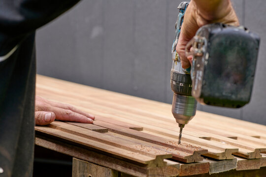 Craftsman Using Drill on Wooden Planks