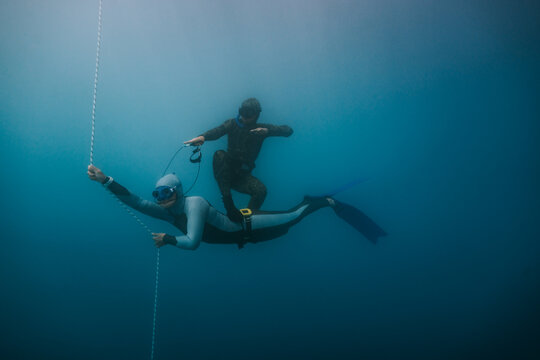 freediver playfully surfing underwater on a friend