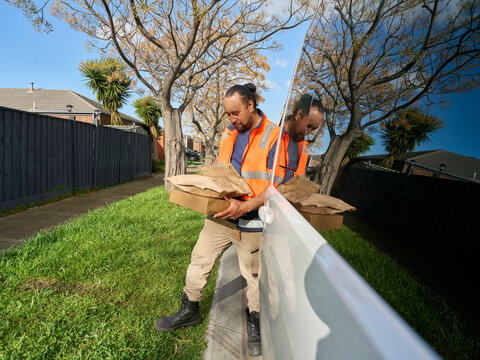 Delivery Worker Carrying Packages Near a Van on a Street