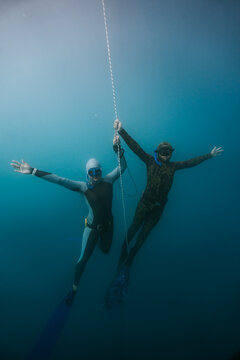 two freedivers playing together in deep lake water