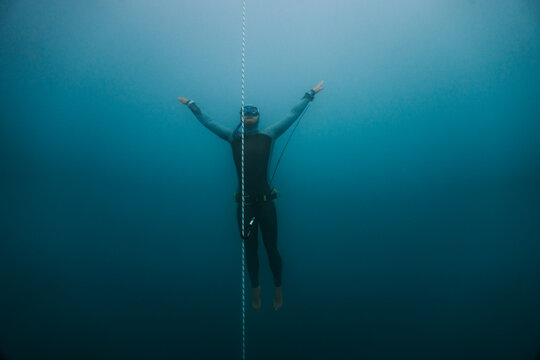 freediver spreading arms in deep lake water