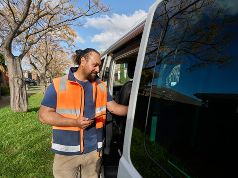 Man in Safety Vest Standing by Van in Urban Area