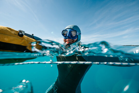 masked freediver at the lake surface in split view