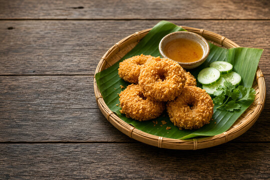 Crispy fried shrimp cakes Tod Mun Goong shaped like donuts served with plum sauce on a bamboo basket