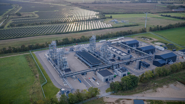 Aerial footage of E-methanol power-to-x plant in Denmark. State-of-the-art Power-to-X facility by green fields and vast solar park showcasing integration of renewable energy and green fuel production