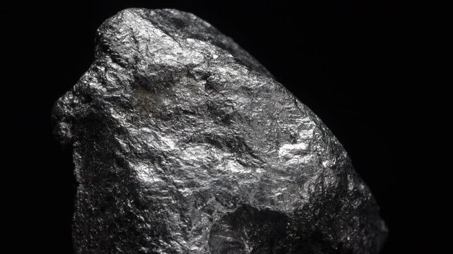 Graphite - soft form of pure carbon - specimen rotating slowly against a black background.