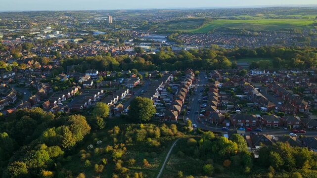 Aerial video over residential housing in Wortley extending toward Elland Road Stadium and the southern Leeds countryside under late afternoon sunlight.