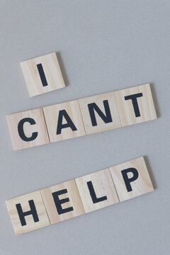 "i cant help" sign composed of wood tiles with black sans serif font on cardboard