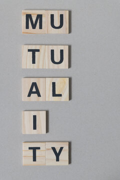 "mutuality" sign composed of wood tiles with black sans serif font on cardboard