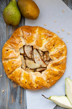 Pear pie. Home pastry. Baked fruit galette served on kitchen napkin. Traditional round treat with delicious golden crust background.