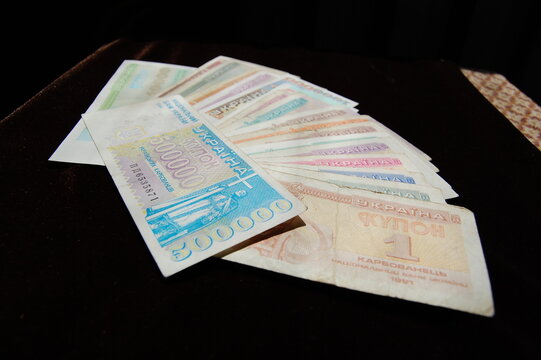 A collection of old Ukrainian hryvnia banknotes spread out on a dark surface.
