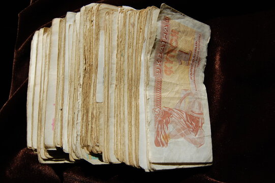 A collection of old Ukrainian hryvnia banknotes spread out on a dark surface.