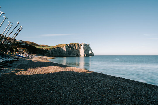 Etretat cliffs, pebble beach, and grounded boats on a clear French morning