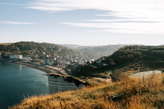 Etretat village nestled between green cliffs and the blue English Channel sea under a morning sky