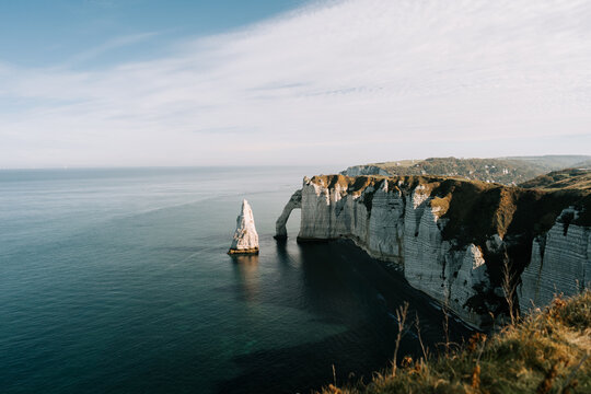White chalk cliffs and natural rock arch in Etretat along the coast of Normandy during the daytime
