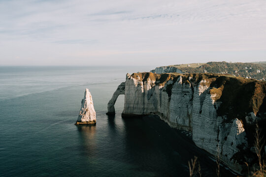 White chalk cliffs of Etretat rise above the Atlantic Ocean on a calm day in Normandy France