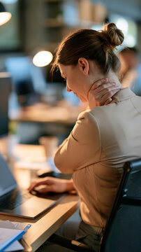 Faceless professional with intense neck pain from prolonged desk work, health issues of sedentary office environments and poor ergonomics, with copy space