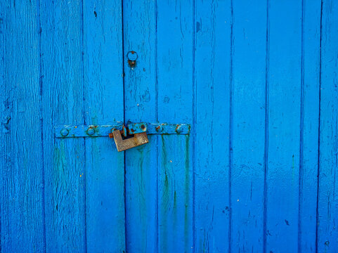 Rusty padlock on a weathered blue wooden door