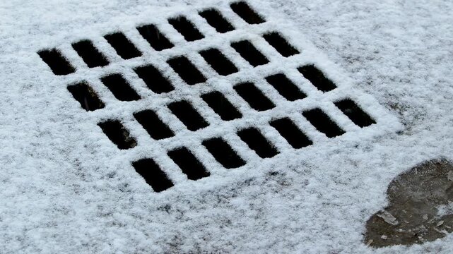 Close up of storm drain covered in fresh snow