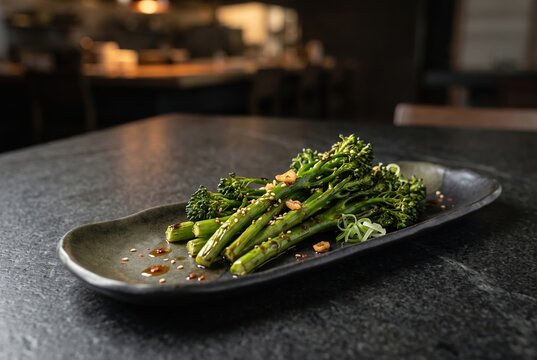 Charred broccolini with chili on black restaurant plate