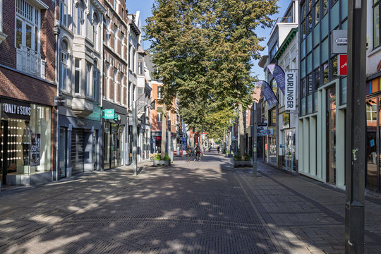 Heerlen, Netherlands - 04 October 2026: Empty pedestrian shopping street in downtown Heerlen lined with retail stores, fashion shops, tree avenues, and historic brick facades.