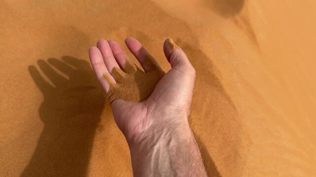 Sand flowing from hands in the desert	