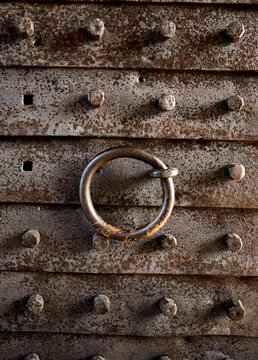 Close up shot of ancient rusty iron gate with large metal bolts and heavy iron ring knocker at Belogradchik Fortress in Bulgaria. Medieval architecture texture and history background concept.
