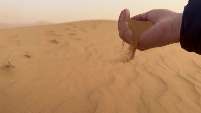 Sand flowing from hands in the desert	