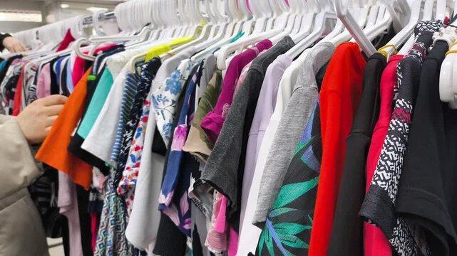 Women's hands choosing clothes from a hanger. Shopping at a second-hand store. Caring about the environment.