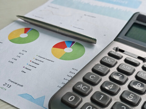 Calculator and financial reports on a desk with charts and graphs showing various data concept