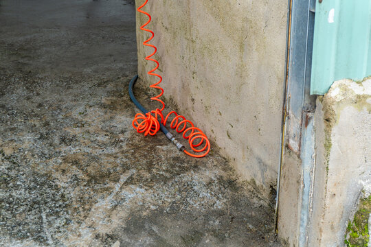 Orange air hose coiled beside a wall in Da Lat Vietnam