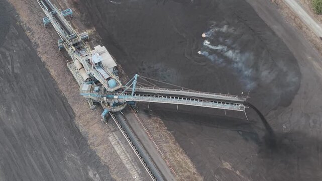 Aerial view of a large coal stacker machine dumping black coal at a mine in South Kalimantan