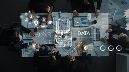 A group of professionals engaged in a business meeting focused on data security, surrounded by digital graphics representing protection and analysis of information. Raster © InfiniteFlow