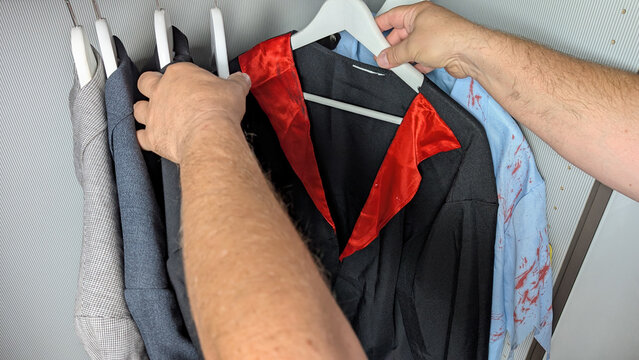 Man selecting a Halloween costume from a closet. 