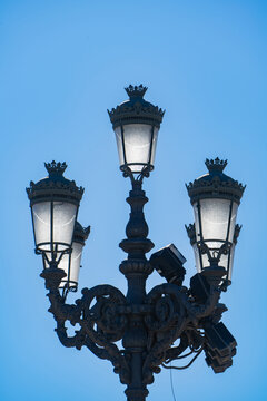 Detail of an elegant Fernandina iron streetlamp with decorative ornamentation, featuring several arms with decorative lights and crowns.