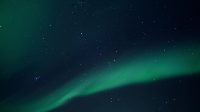 Green aurora borealis ribbon sweeping across starry night sky with soft diffuse glow and tranquil celestial mood, wide diagonal composition from low viewpoint to horizon