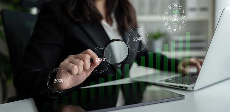 A business professional conducts an analysis of growth trends and future projections with a magnifying glass and digital graphs in a sleek office environment. Gantry