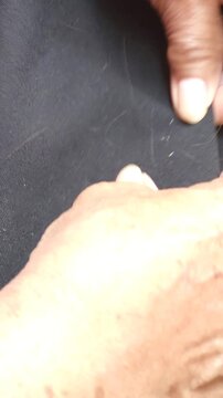 Hands Using Fine Nit Comb over Black Fabric for Lice Removal