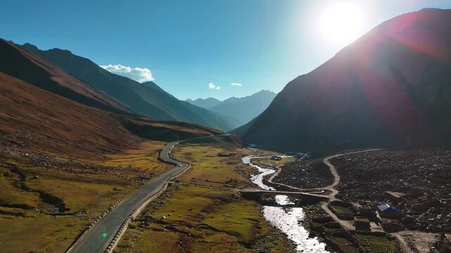 Drone view video clip highlighting a high-altitude highway, riverbed rocks, and rural shelters in the Himalayan region of Pakistan.