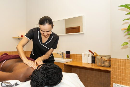 Woman masseuse giving back massage to client in spa