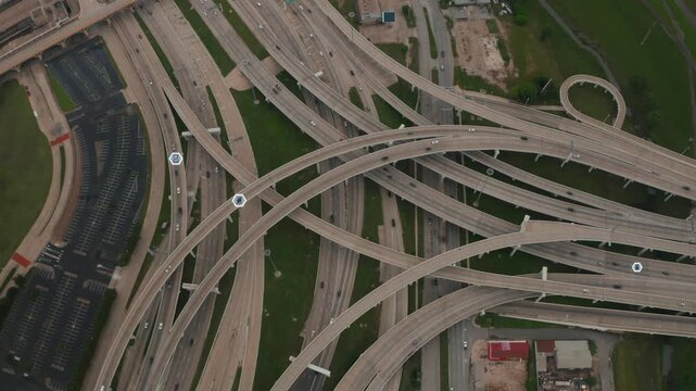 Top down view of a multi level highway stack interchange in Dallas with autonomous vehicles tracked by hexagon data tags, smart city traffic and AI technology concept with digital overlay