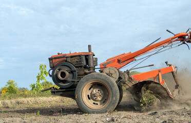 Tractor plows field with disc harrow, turning soil and raising dust. Farm machinery cuts through crop stubble beneath open sky, preparing farmland for planting as rotating discs till ground. © Віталій Б.