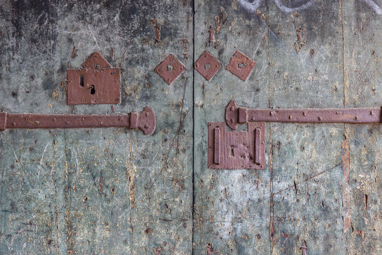 Old rusty iron locks and bolts on ancient wooden door background in Venice, Italy