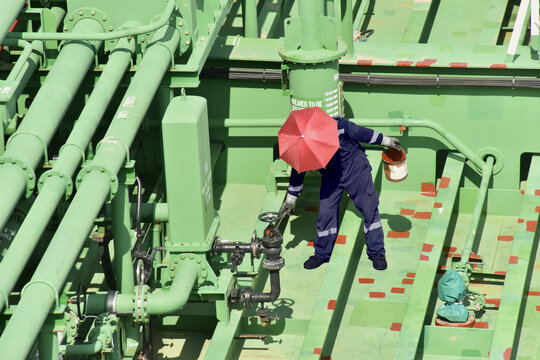 a  crewman onboard tanker is doing spot maintenance of deck.