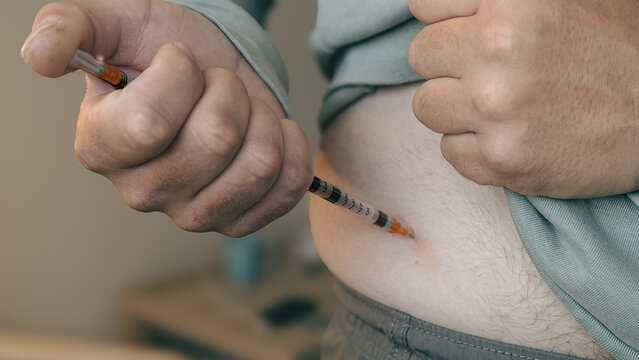 Insulin Injection and Hormone Therapy Closeup.a person administering an injection into the abdomen, illustrating insulin therapy, diabetes management, vaccination, hormone replacement treatment