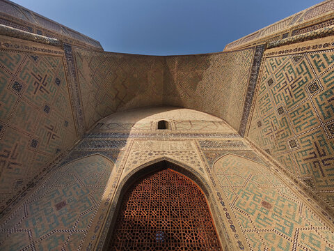 Bibi-Khanym Mosque portal in Samarkand with intricate tilework and wooden lattice screen viewed from below. Ideal for travel publications, cultural heritage materials, and architectural studies.