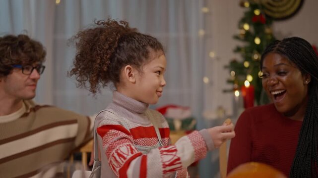 Christmas family celebrating winter holiday tradition with joyful child, woman and man sharing warm relationship, gift, conversation and happiness home beside decorated tree during indoor seasonal