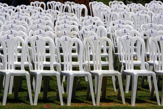 Rows of empty white folding chairs for an outdoors event