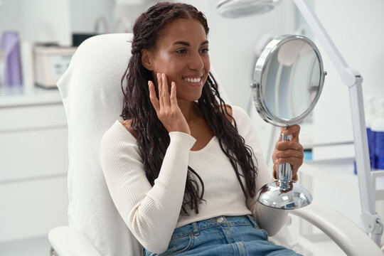 Forehead wrinkles and early skin aging concerns during a facial self examination. Woman touches her forehead while looking in a mirror at a cosmetic clinic before consultation.