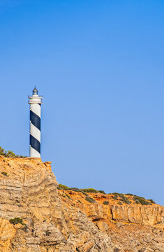 Ibiza, Balearic Islands, Spain: view of the Punta Moscarter Lighthouse (Faro de Moscarter), an active black and white striped lighthouse near Portinatx, on the northern coast of the island